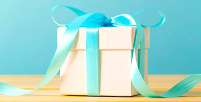 Photo of a white box wrapped up with a blue bow